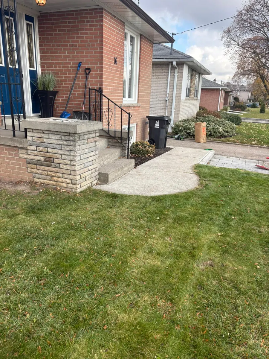 Brampton front yard after a fall cleanup — lawn cleared of leaves, bed edged, and a kraft yard-waste bag out at the curb